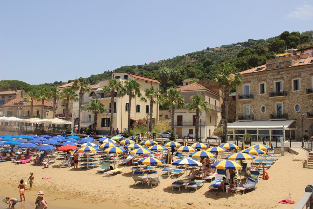 sandy beach with umbrellas and historic buildings and promenade behind