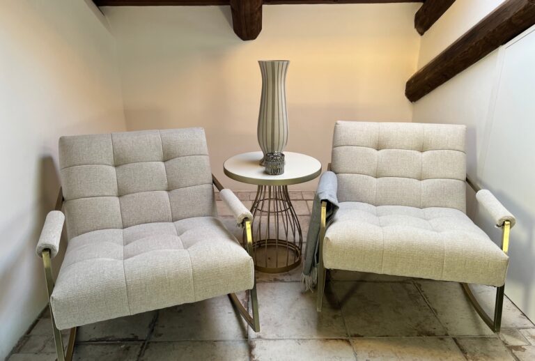 2 low soft chairs in grey with a round glass table and vase in between