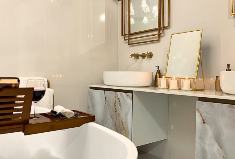 Close up of white bath, glass of read wine and sink and mirrors