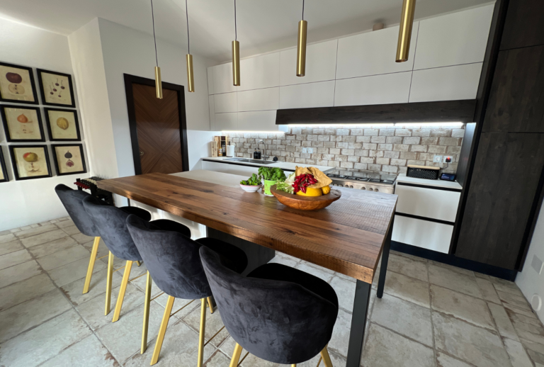 Luxury kitchen with island wooden top and blue velvet stools with brass lights above