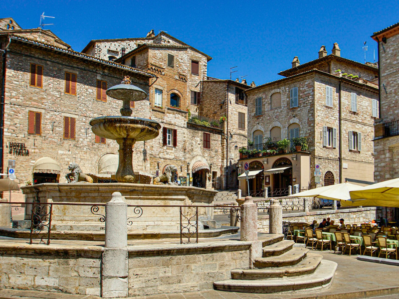 Fountain with stone lions in an Italalian piazza with buildings and a restaurant