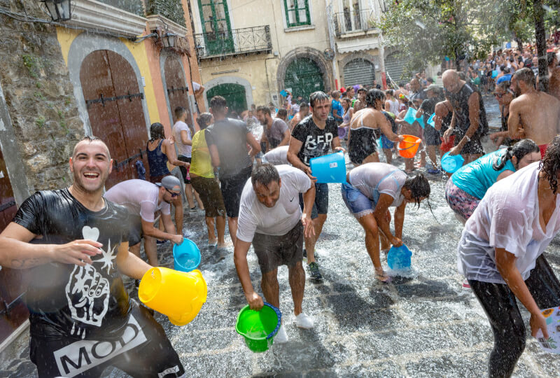 People lining the water-filled streets with buckets at the A Chiena water festival in Campagna in Campania
