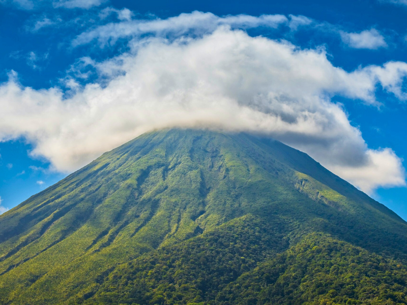 volcano with green vegetation covered at the top by clouds