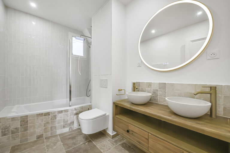 Bath with shower and toilet and vanity unit and round mirror